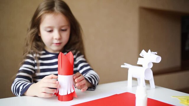 paper craft for kids. DIY toy Saint Nicholas and white horse for sinterklaas day. create art for children. girl considers and turns toy