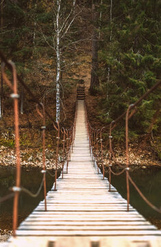 Fototapeta Beautiful rope hanging wooden bridge over the river. autumn landscape