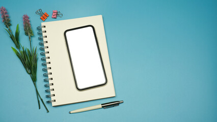 Flat lay, Workspace back to school and technology education concept on pink table desk with blank screen phone on blank notepad, green plant and stationery, Top view with copy space