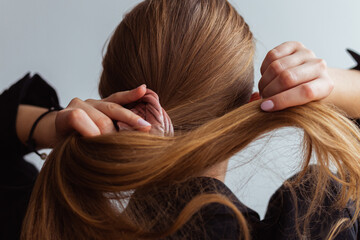 Natural blonde woman doing a ponytail, holding her hair, stop motion, back view, 