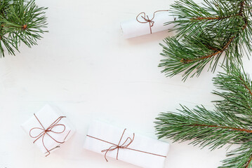 Elegant Christmas holiday composition with fresh fir tree branches and wrapped gift boxes with template for design on white color background flat lay