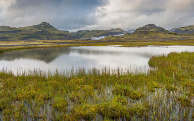 Landscape in the south of Iceland with mountains, a glacier and a lake under an overcast sky