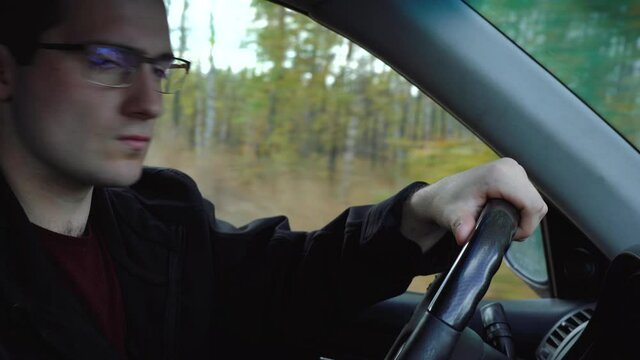 man drives a car and smiles at the camera