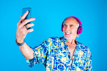 Senior man using smartphone listening playlist streaming online - Old man using smartphone taking selfie