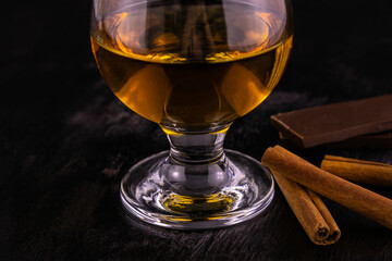 A glass of cognac chocolate and cinnamon sticks