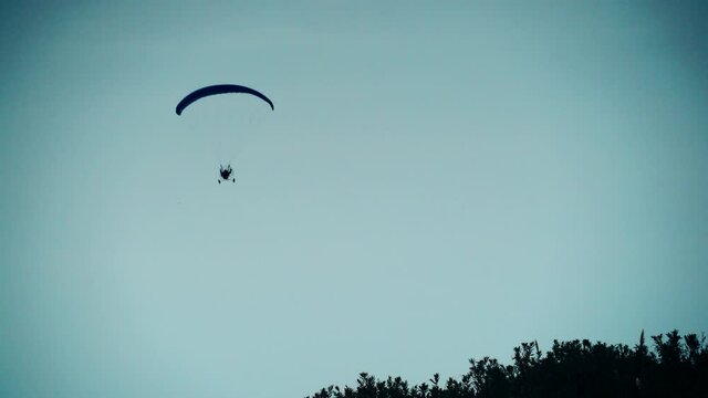 Paragliding. Extreme sport. Paraglider silhouette flying in the evening sky.