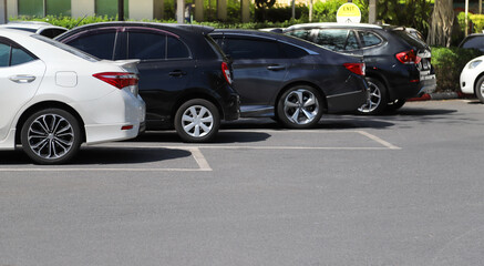 Closeup of rear side of white car with  other cars parking in outdoor parking area in bright sunny day. 