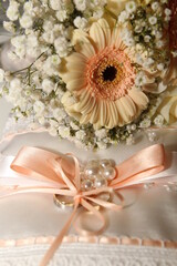 pink bow with white pearls and pink themed flower bouquet beside it