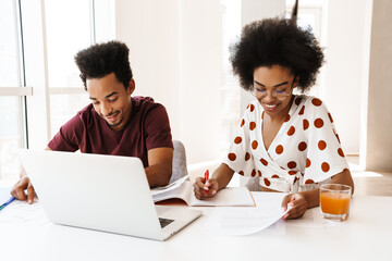 Beautiful couple sitting at the kitchen with laptop