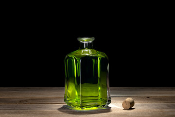 Vintage bottle of yellow liquid on wooden table. Black background. 
