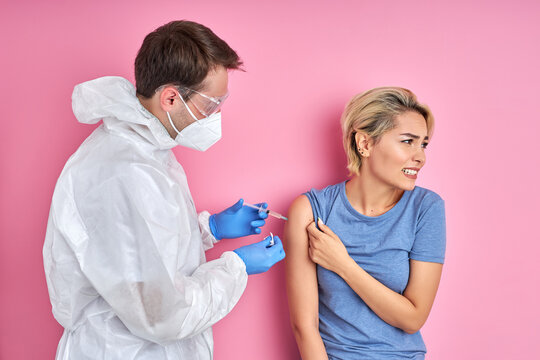 male doctor giving vaccine shot to frightened caucasian woman, female is afraid of injections. prevention, protection and immunization concept