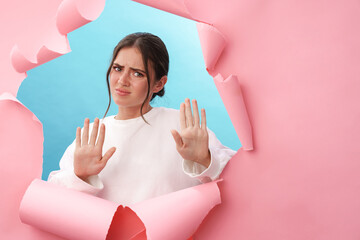 Caucasian young strict woman frowning and doing stop gesture with hands