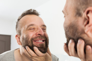 Fototapeta premium Man looking at beard in mirror