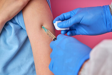 close-up nurse vaccinating patient using the syringe, doctor vaccinating kid boy, isolated on pink background. sterile injectable upper arm. injection