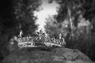 mysterious and magical photo of king crown in the England woods over stone. Medieval period concept. black and white image