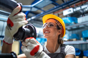 Factory worker checking quality of metal parts for automobile industry.