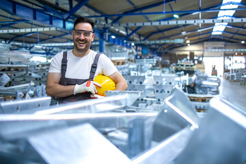 Portrait of industrial engineer. Smiling factory worker with hard hat standing in factory...