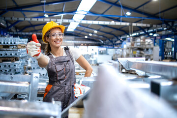 Portrait of female factory worker holding thumbs up.