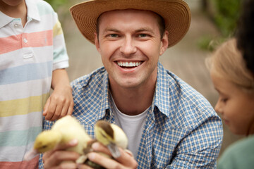 Fototapeta premium portrait of happy adult man teacher showing ducklings to pupils children in the garden, smile. play with and take care of animals