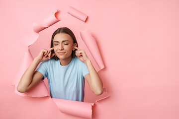 Fototapeta premium Young caucasian brunette woman plugging her ears with fingers