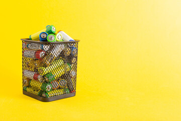 Basket with waste batteries on a yellow background. Battery recycling concept, business, copy space...