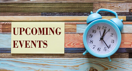 Upcoming events message on notepad with alarm clock on wooden table
