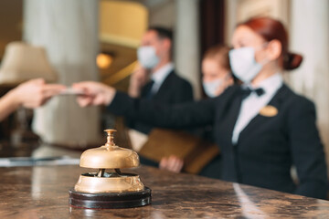 Check in hotel. receptionist at counter in hotel wearing medical masks as precaution against virus....