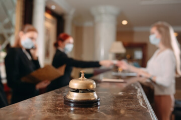 Check in hotel. receptionist at counter in hotel wearing medical masks as precaution against virus. Young woman on a business trip doing check-in at the hotel