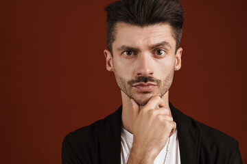 Photo of confident man looking at camera and touching his chin