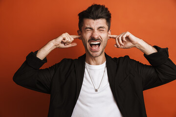 Photo of young displeased man plugging his ears with fingers