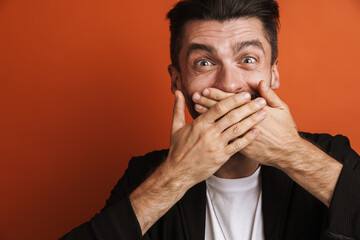 Photo of young happy man covering his mouth with hands