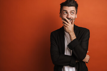 Photo of young surprised man covering his mouth and looking with wonder