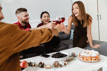 Image of joyful multinational friends eating pie and drinking wine