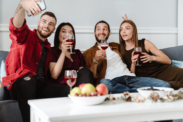 Image of friends taking selfie on mobile phone while drinking wine