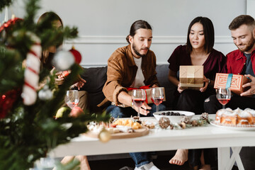 Image of friends giving presents to each other while drinking wine