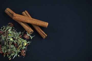 Dried cinnamon sticks and herbal tea on a black background
