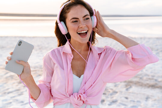 Optimistic young girl in sunglasses listening music