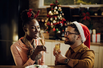 Happy couple drinking Champagne while celebrating New Year at home.