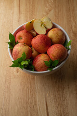 Many Gala apples in a white bowl Lay on the wooden floor