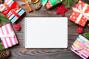 Obraz premium Top view of a notebook on wooden holiday background made of fir tree and New Year decorations. Christmas time concept