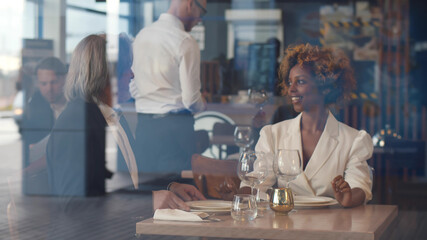 View through window of multiethnic couple in modern fashionable restaurant