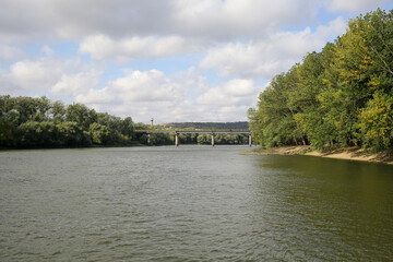 Fototapeta premium River bridge. A steady flow of water. Trees on both sides of the river.