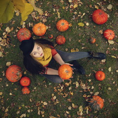 Beautiful girl is sitting on the grass. Top view. She is holding a pumpkin. 