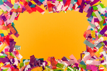 top view of colorful bright confetti frame on orange background