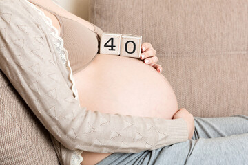Pregnant woman in white underwear on bed in home holding calendar with weeks 40 of pregnant....