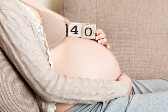 Pregnant woman in white underwear on bed in home holding calendar with weeks 40 of pregnant. Maternity concept. Expecting an upcoming baby