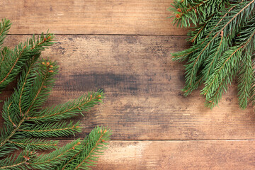 Christmas background with fir branches. Winter holidays frame with evergreen twigs on wooden board table. Flat lay, copy space