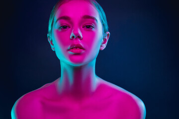 Tender. Portrait of female fashion model in neon light on dark studio background. Beautiful caucasian woman with trendy make-up and well-kept skin. Vivid style, beauty concept. Close up. Copyspace