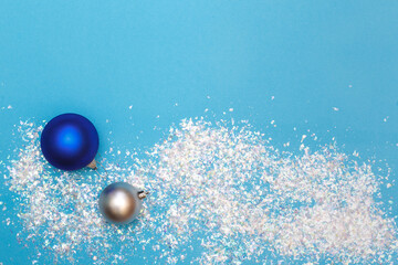 Blue background with artificial snow, sequins and balls for the Christmas tree. Top view with space