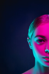 Half full. Portrait of female fashion model in neon light on dark studio background. Beautiful caucasian woman with trendy make-up and well-kept skin. Vivid style, beauty concept. Close up. Copyspace